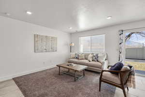 Living room with light tile patterned floors, a textured ceiling, and recessed lighting