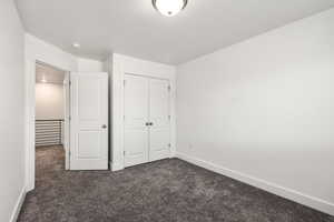 Unfurnished bedroom featuring dark carpet and a closet