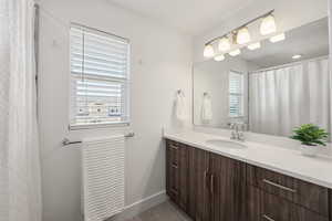 Bathroom featuring a shower with shower curtain, vanity, and light tile patterned floors