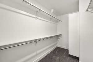 Walk in closet featuring dark carpet