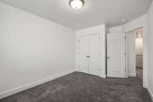Unfurnished bedroom featuring dark colored carpet and a closet
