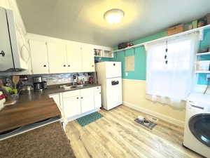 Kitchen featuring area with dark countertops, and washer dryer combo.
