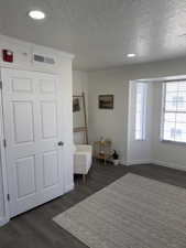 Living area featuring dark wood finished floors, ornamental molding, a textured ceiling, and recessed lighting