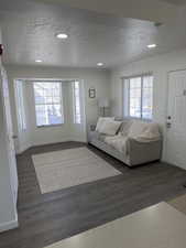 Living area with dark wood finished floors, a textured ceiling, and recessed lighting