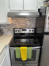 Kitchen with stainless steel appliances, white cabinets, light countertops, and tasteful backsplash