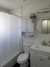 Full bath featuring vanity, shower / tub combo, and a textured ceiling