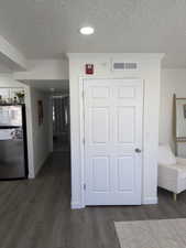 Corridor featuring crown molding, dark wood-style flooring, and a textured ceiling