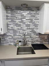 Kitchen featuring white cabinets, backsplash, and light stone countertops