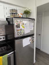 Kitchen view of stainless steel appliances, dark wood-style flooring, extractor fan, and white cabinets