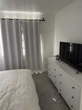 Bedroom featuring dark carpet and baseboards