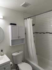 Full bathroom with shower / tub combo with curtain, vanity, and a textured ceiling