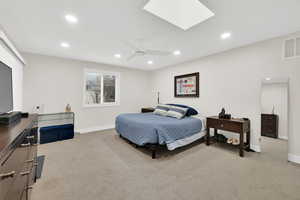 Bedroom featuring a skylight, light colored carpet, a ceiling fan, and recessed lighting