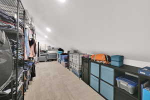 Walk in closet with lofted ceiling and light colored carpet