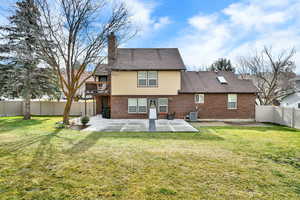 Rear view of house with a patio, a chimney, a fenced backyard, brick siding, and a shingled roof