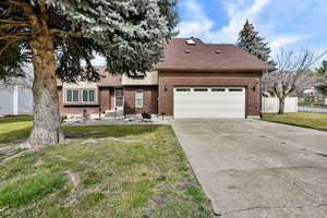 View of front of house with a shingled roof, brick siding, driveway, and a garage