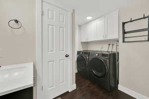 Laundry room featuring dark wood-type flooring, separate washer and dryer, and cabinet space