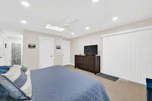 Bedroom featuring carpet, ensuite bathroom, a ceiling fan, a skylight, and recessed lighting