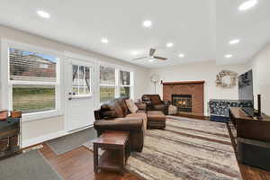 Living room featuring dark wood-style floors, a fireplace, a ceiling fan, and recessed lighting