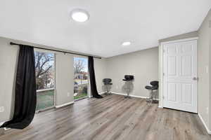 Exercise room with light wood-type flooring and baseboards