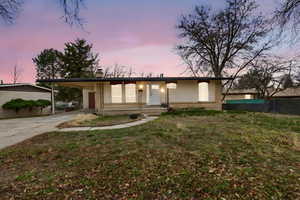 View of front facade with driveway, an attached carport, brick siding, and a porch