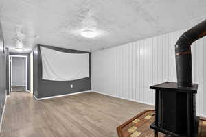 Unfurnished living room with a wood stove, light wood-style flooring, and a textured ceiling