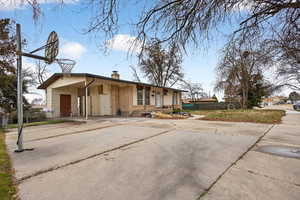 View of front of house featuring driveway, a chimney, an attached carport, and brick siding