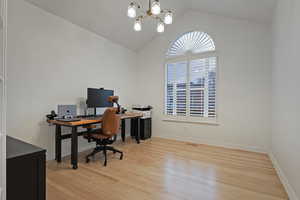 Office area featuring light wood-style floors and suspended lighting