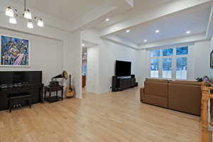 Living room with a tray ceiling, light wood-type flooring, and a chandelier