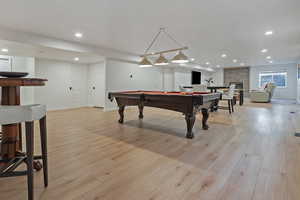Rec room with pool table, light wood-style floors, recessed lighting, and a large fireplace
