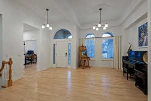 Entrance foyer featuring hanging lights, light wood finished floors, and a high ceiling