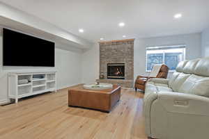 Living room with light wood-type flooring, recessed lighting, and a fireplace