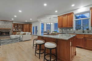 Kitchen with light stone countertops, a breakfast bar area, wood finish cabinetry, open floor plan, and a kitchen island