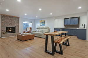 Living room featuring light wood-type flooring, recessed lighting, and a fireplace