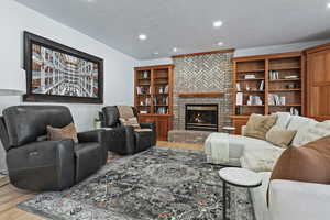 Living room with light wood finished floors, recessed lighting, and a fireplace