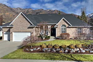 View of front of house featuring a mountain view, brick siding, driveway, and a front yard