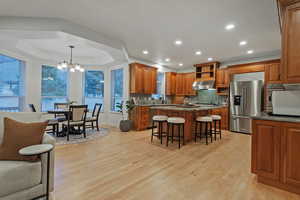 Kitchen with a kitchen breakfast bar, wood finish cabinets, dark stone countertops, stainless steel appliances, and a tray ceiling