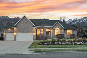 View of front of home with a mountain view, driveway, brick siding, and a garage