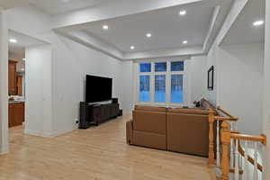 Living room featuring light wood-type flooring, recessed lighting, and a raised ceiling