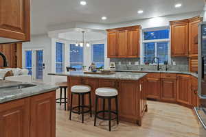 Kitchen featuring wood finish cabinets, light stone counters, light wood-style floors, and a kitchen breakfast bar