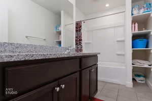 Full bath with vanity, light tile patterned floors, and shower / tub combo