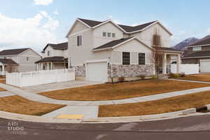 Traditional-style house with driveway, stone siding, stucco siding, an attached garage, and a porch
