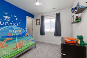 Bedroom featuring carpet floors, a ceiling fan, and a textured ceiling