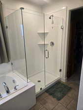 Bathroom with a stall shower, a walk in closet, a garden tub, and light tile patterned floors