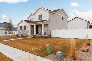 View of front of home with covered porch, stucco siding, and stone siding