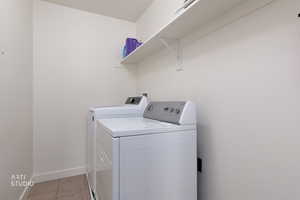 Laundry room featuring light tile patterned floors and washer and clothes dryer