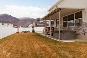 Fenced backyard featuring a hot tub, a patio area, and a mountain view