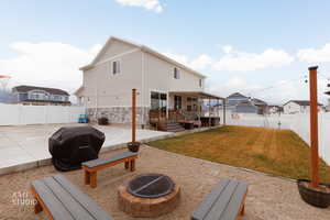 Rear view of property featuring a patio, a fenced backyard, an outdoor fire pit, and stone siding