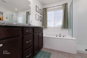 Full bath featuring a stall shower, vanity, light tile patterned flooring, and a garden tub