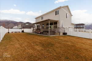 Rear view of property featuring a mountain view, a fenced backyard, a patio, and stone siding