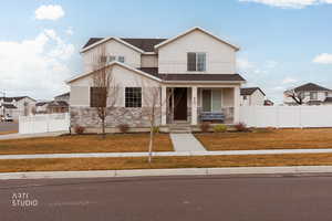 View of front of house featuring covered porch, stone siding, and stucco siding